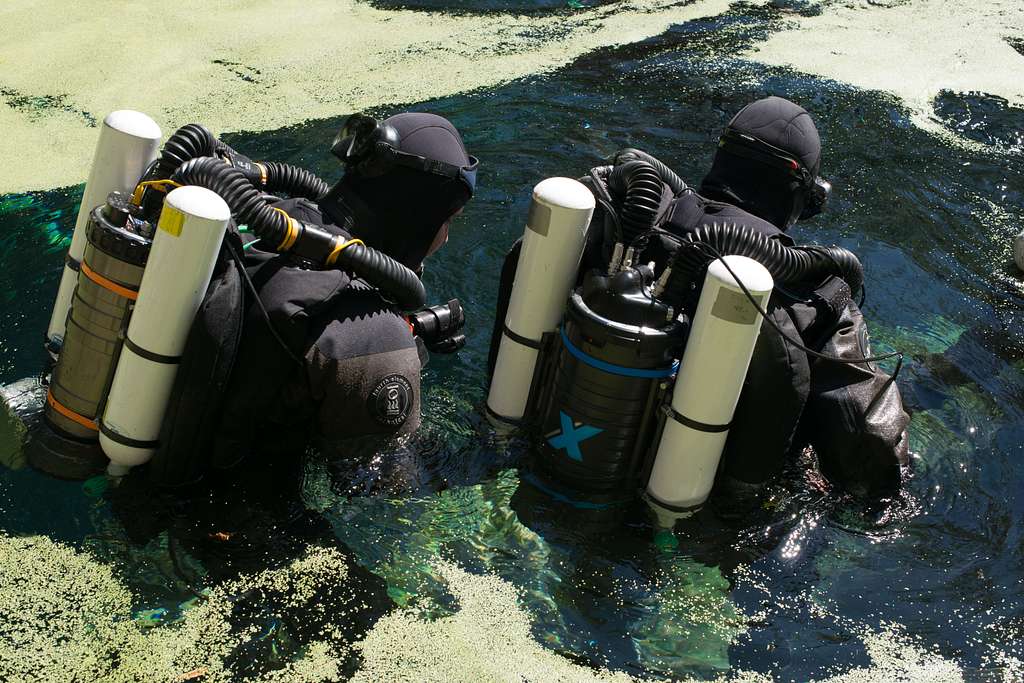 Two divers wearing closed circuit rebreathers entering the water